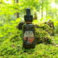 Tomte Beard & Hair Tonic sits atop a mossy log with green forest in the background.