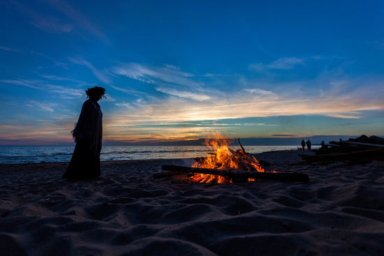 Unrecognizable people celebrating Litha with bonfires on beach