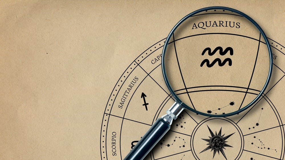 The imprint of the zodiac sign Aquarius on old paper is enlarged with a lens