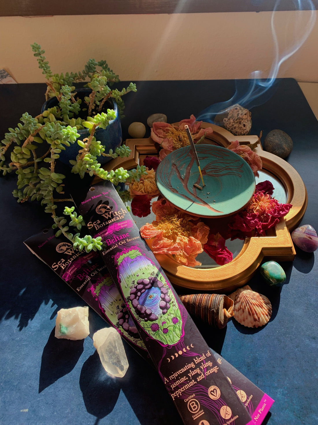Sea Witch Botanicals Beltane™ Incense burning with variety of crystals, flowers, shells, and plants