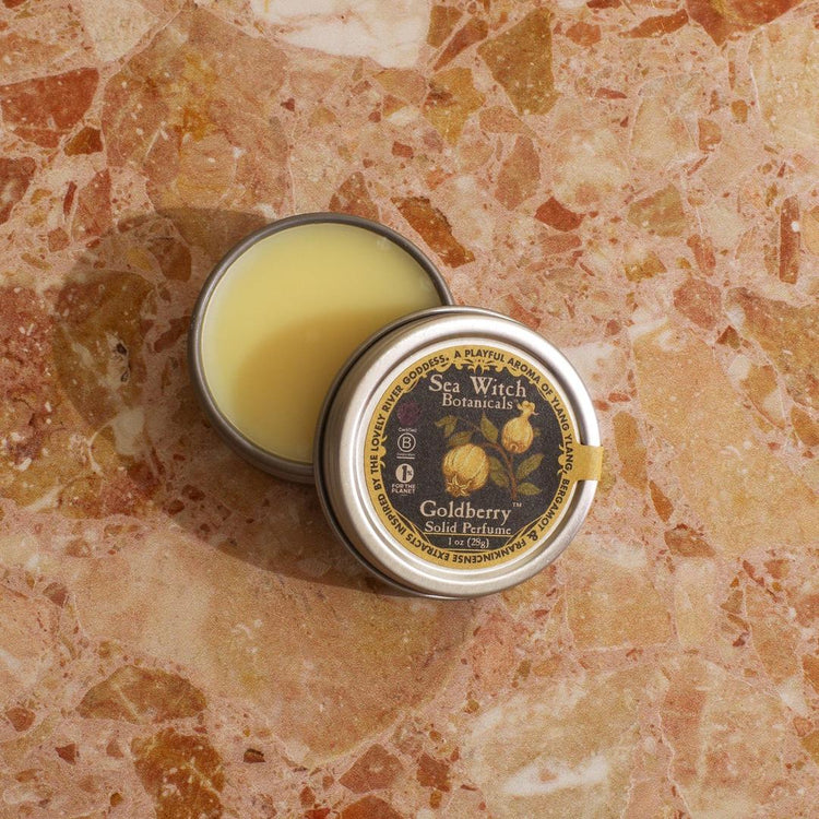 Small tin of balm with a decorative label on a textured surface