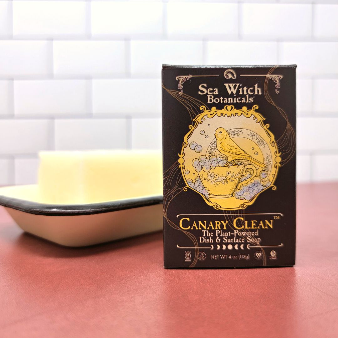 Canary Clean in a box stands on a red countertop with white backsplash in front of a soap dish holding a bare bar.