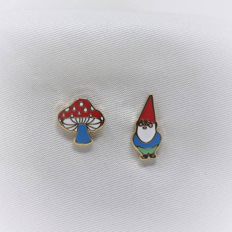 Yellow Owl Workshop Mismatched Stud Earrings - one is an amanita muscaria mushroom and the other is a white-bearded gnome with a red hat.