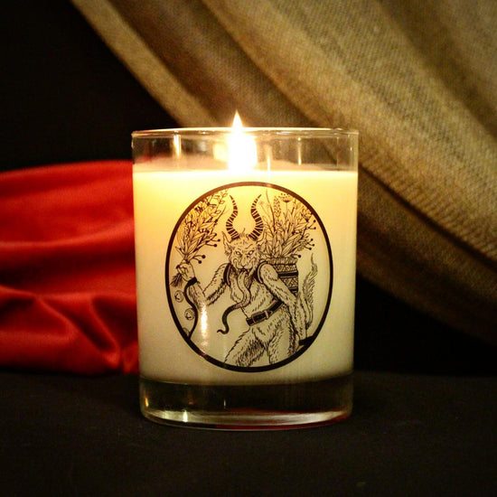 Essential oil Krampus 2022 candle on a black set with red and gold fabrics in the background
