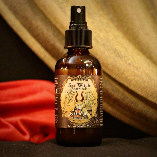 Limited Edition essential oil Krampus scented veil perfume and room spray on a black set with red and gold fabrics in the background.