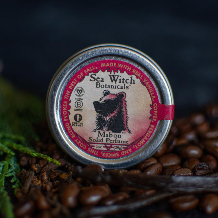 Mabon Limited Edition Solid Perfume in its 10z tin, on a bed of coffee beans, vanilla beans, and cedar boughs.