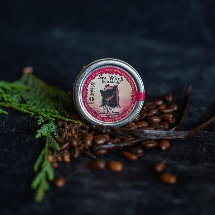 Mabon Limited Edition Solid Perfume in its 10z tin, on a bed of coffee beans, vanilla beans, and cedar boughs.
