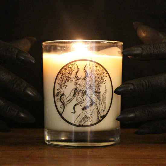 soot-black hands with claw-like nails around a limited edition Krampus candle